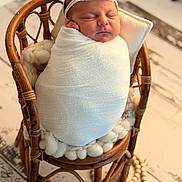 Eleya participe au concours pour gagner de l'argent avec cette photo : newborn, baby, sleeping, wrapped, blanket, headband, chair, wooden_chair, cushion, cozy, indoors, portrait, infant, peaceful, soft_texture, cute, resting, closeup, warm, decor
