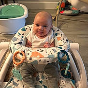 Morgan is registered to the contest to win money with this photo: baby, infant, baby_walker, socks, pants, toys, floor, baby_bathtub, playful, smiling, indoors, carpet, furniture, child, person, seat, patterned, cute, tongue_out, happy