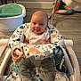 baby, infant, baby_walker, socks, pants, toys, floor, baby_bathtub, playful, smiling, indoors, carpet, furniture, child, person, seat, patterned, cute, tongue_out, happy