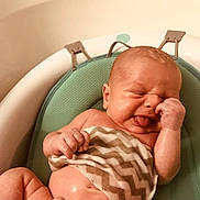 Morgan is registered to the contest to win money with this photo: baby, infant, face, skin, tongue, hand, arm, bath, bathroom, seat, cushion, pattern, zigzag, expression, newborn, cute, child, water, wet, human