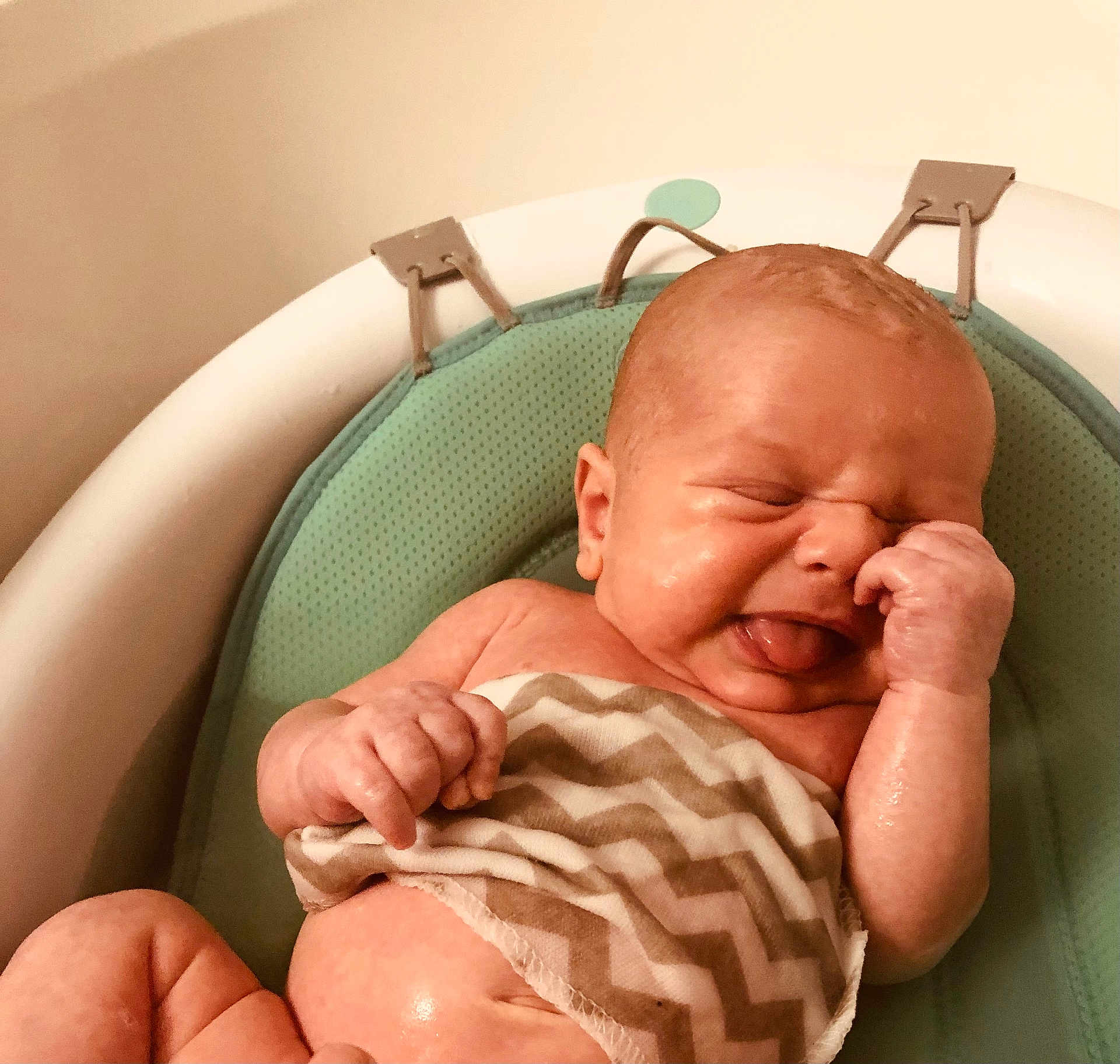 Morgan is registered to the contest to win money with this photo: baby, infant, face, skin, tongue, hand, arm, bath, bathroom, seat, cushion, pattern, zigzag, expression, newborn, cute, child, water, wet, human