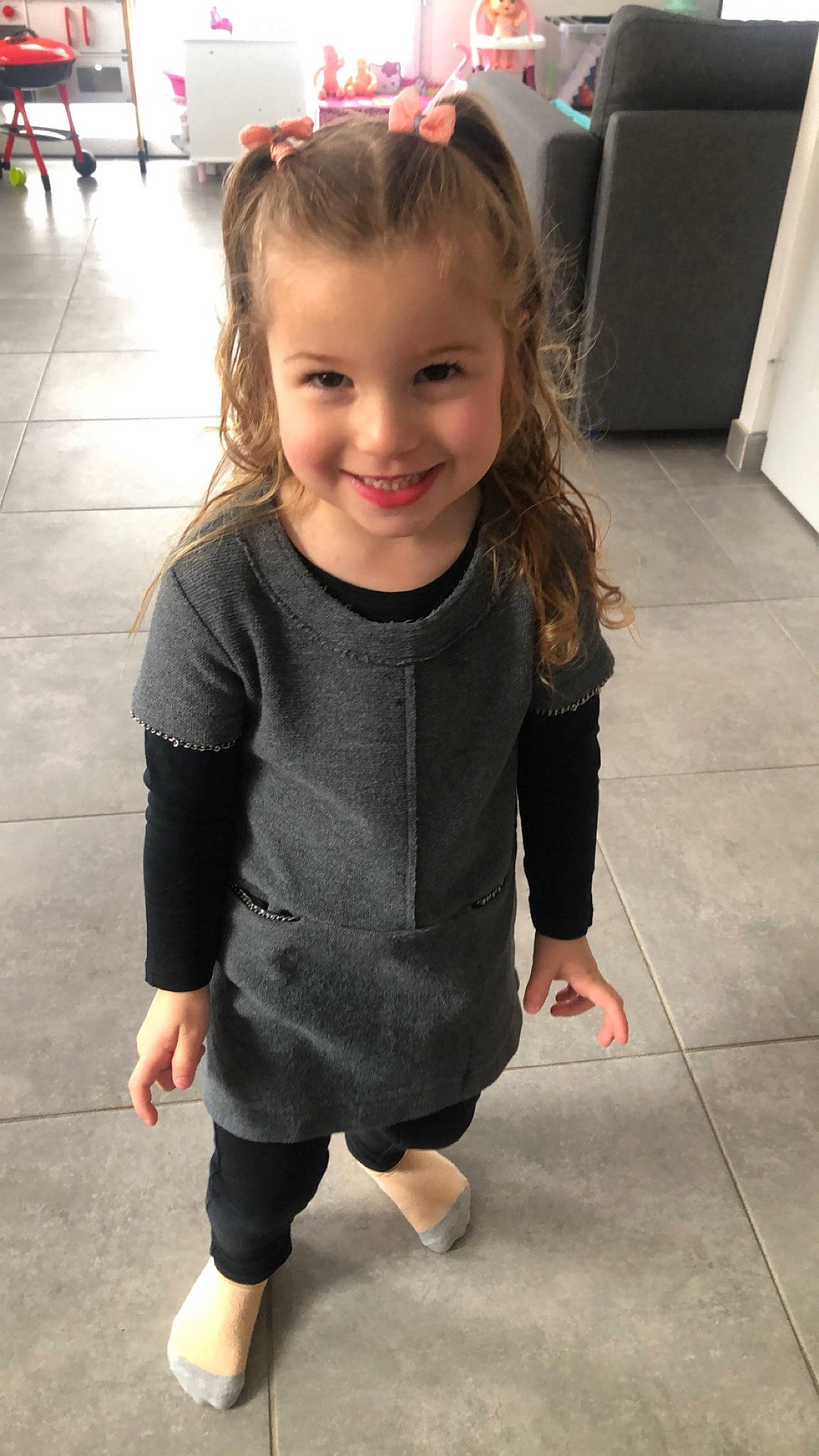 Emilia a rejoint le concours — aidez-le/la à gagner de superbes lots ! baby_toddler_clothing, blond, child, dress, facial_expression, flooring, fun, gesture, hairstyle, happy, human_leg, joint, joy, one_piece_garment, person, skin, sleeve, smile, standing, toddler