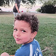 Yassine a rejoint le concours — aidez-le/la à gagner de superbes lots ! child, boy, smile, grass, tree, park, blanket, outdoor, nature, curly_hair, shorts, tshirt, sky, greenery, person, daylight, play, relax, fun, casual