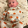 baby, infant, child, portrait, smiling, happy, lying_down, blanket, onesie, pumpkin_pattern, polka_dots, clothing, face, eyes, hair, indoor, cozy, couch, soft_blanket, photography