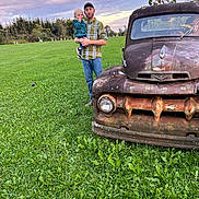 Raelynn is registered to the contest to win money with this photo: child, toddler, adult, man, father, parent, outdoor, field, grass, vintage_car, rusty_truck, ford, vehicle, family, portrait, plaid_shirt, baseball_cap, sunset, cloudy_sky, rural