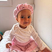 Alma participe au concours pour gagner de l'argent avec cette photo : toddler, child, baby, smiling, pink_hat, pink_skirt, white_shirt, sitting, bed, cute, indoor, portrait, happy, face, headwear, clothing, person, skin, eyes, hand