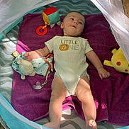 Milann a rejoint le concours — aidez-le/la à gagner de superbes lots ! baby, infant, onesie, blanket, purple_towel, play_tent, mesh_cover, plush_toy, rattle, pacifier, outdoor, sand, leaves, sunlight, shade, reclining, face, head, feet, toy_giraffe