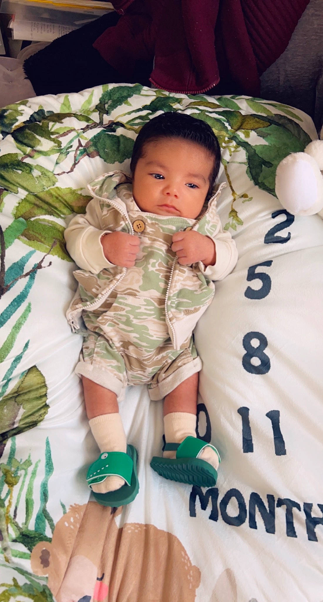 Chris is registered to the contest to win money with this photo: baby, baby_toddler_clothing, bedding, camouflage, child, comfort, cool, finger, green, hand, happy, linens, military_camouflage, pattern, person, skin, sleeve, textile, thumb, toddler