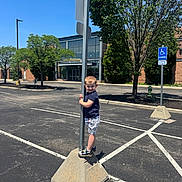 Maksym joined the competition — help win amazing prizes! asphalt, blue_sky, boy, casual_clothing, child, concrete_base, daytime, hand_holding, nature, outdoor, parking_lot, person, playful, pole, shorts, smile, sneakers, standing, sunny, tree