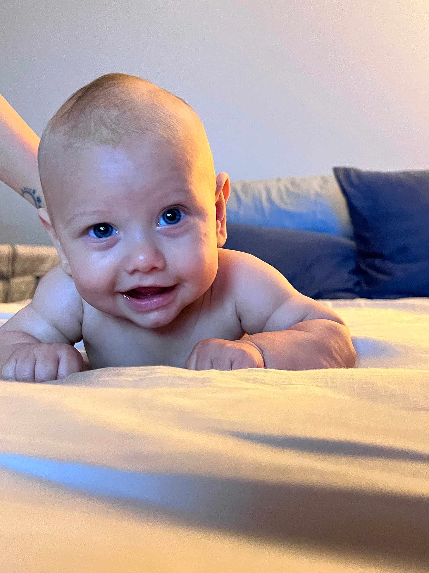 Kyro is registered to the contest to win money with this photo: baby, smiling, blue_eyes, lying_down, bed, pillow, skin, arm, hand, infant, close_up, cute, happy, indoors, child, person, portrait, soft_light, support, background