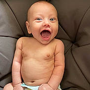 Kyro is registered to the contest to win money with this photo: baby, infant, smiling, diaper, happy, cute, skin, face, fist, sitting, child, young, cushion, comfort, expression, indoors, human, portrait, closeup, joyful