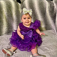 Alexandra joined the competition — help win amazing prizes! baby, child, smile, purple_dress, headband, silver_bow, silver_shoes, sitting, blanket, couch, pillow, indoor, cute, happy, portrait, infant, fashion, clothing, footwear, face