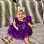 baby, child, smile, purple_dress, headband, silver_bow, silver_shoes, sitting, blanket, couch, pillow, indoor, cute, happy, portrait, infant, fashion, clothing, footwear, face