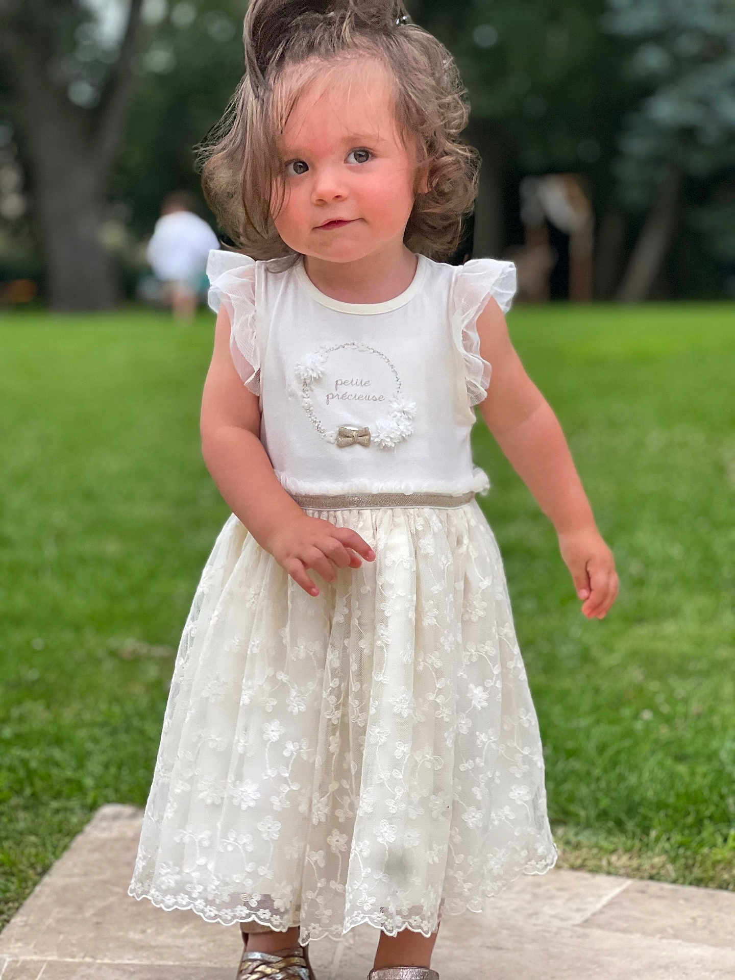 Alba participe au concours pour gagner de l'argent avec cette photo : toddler, child, girl, white_dress, curly_hair, outdoor, grass, trees, greenery, stone_path, portrait, summer, cute, innocence, young_child, fashion, footwear, standing, nature, daylight