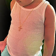 Armanii is registered to the contest to win money with this photo: child, toddler, boy, tank_top, shorts, barefoot, necklace, cross, portrait, indoor, soft_lighting, cute, young_child, person, standing, casual_clothing, skin, hair, expression, serious