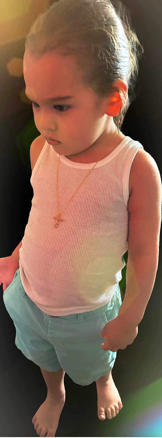 Armanii is registered to the contest to win money with this photo: child, toddler, boy, tank_top, shorts, barefoot, necklace, cross, portrait, indoor, soft_lighting, cute, young_child, person, standing, casual_clothing, skin, hair, expression, serious