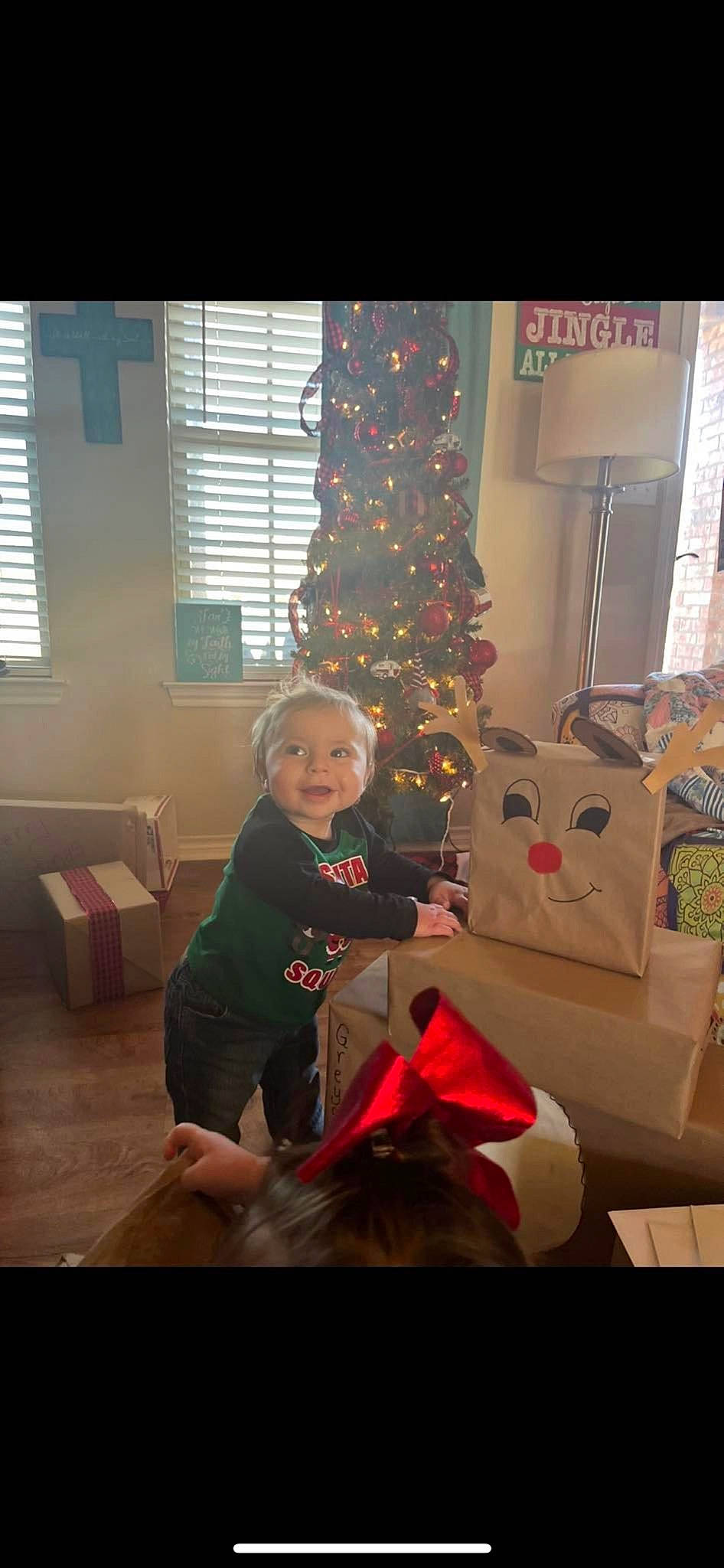 Greyson is registered to the contest to win money with this photo: carmine, christmas, christmas_decoration, christmas_eve, christmas_ornament, christmas_tree, event, fun, holiday, holiday_ornament, interior_design, lap, ornament, person, room, sitting, tree, window, window_blind, winter