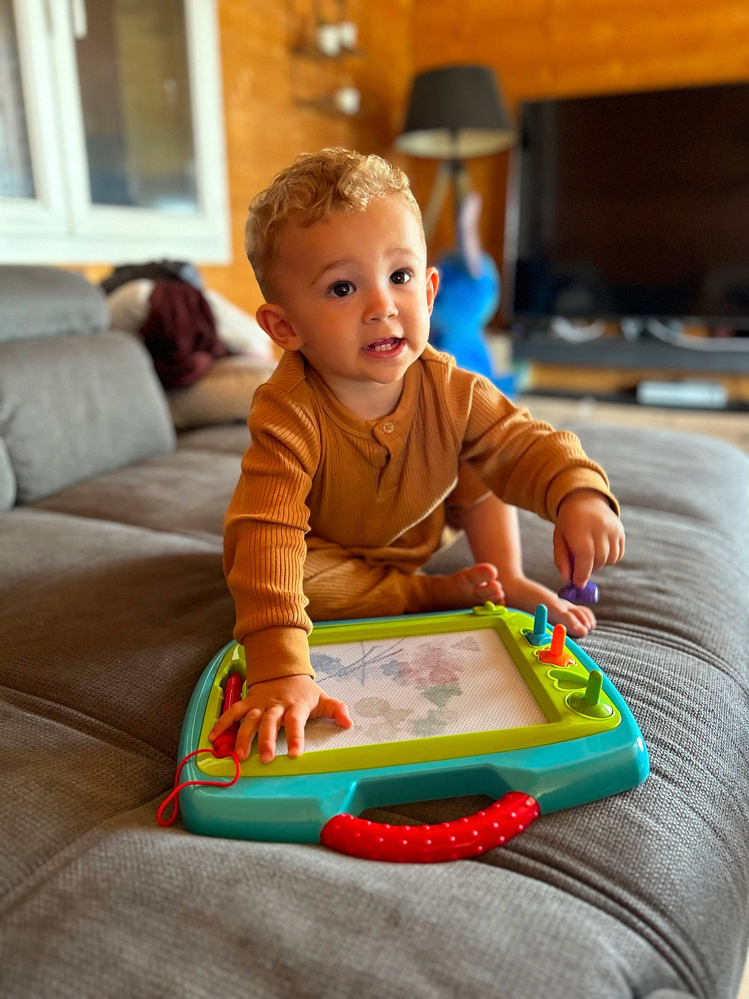 Luiz participe au concours pour gagner de l'argent avec cette photo : baby, baby_playing_with_toys, baby_toddler_clothing, chair, child, comfort, couch, flooring, fun, leisure, person, play, room, sharing, sitting, smile, toddler, wood