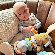 Koleson is registered to the contest to win money with this photo: baby, child, blue_eyes, plush_toy, bunny, overalls, button, blue_shoes, leather_chair, pillow, window, natural_light, indoor, cute, infant, sitting, toy, soft_toy, cozy, portrait