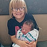 Daniel is registered to the contest to win money with this photo: child, newborn, baby, sibling, smiling, sleeping, glasses, blonde_hair, portrait, indoor, couch, sitting, holding_baby, swaddled, family, infant, home, hands, clothing, photography