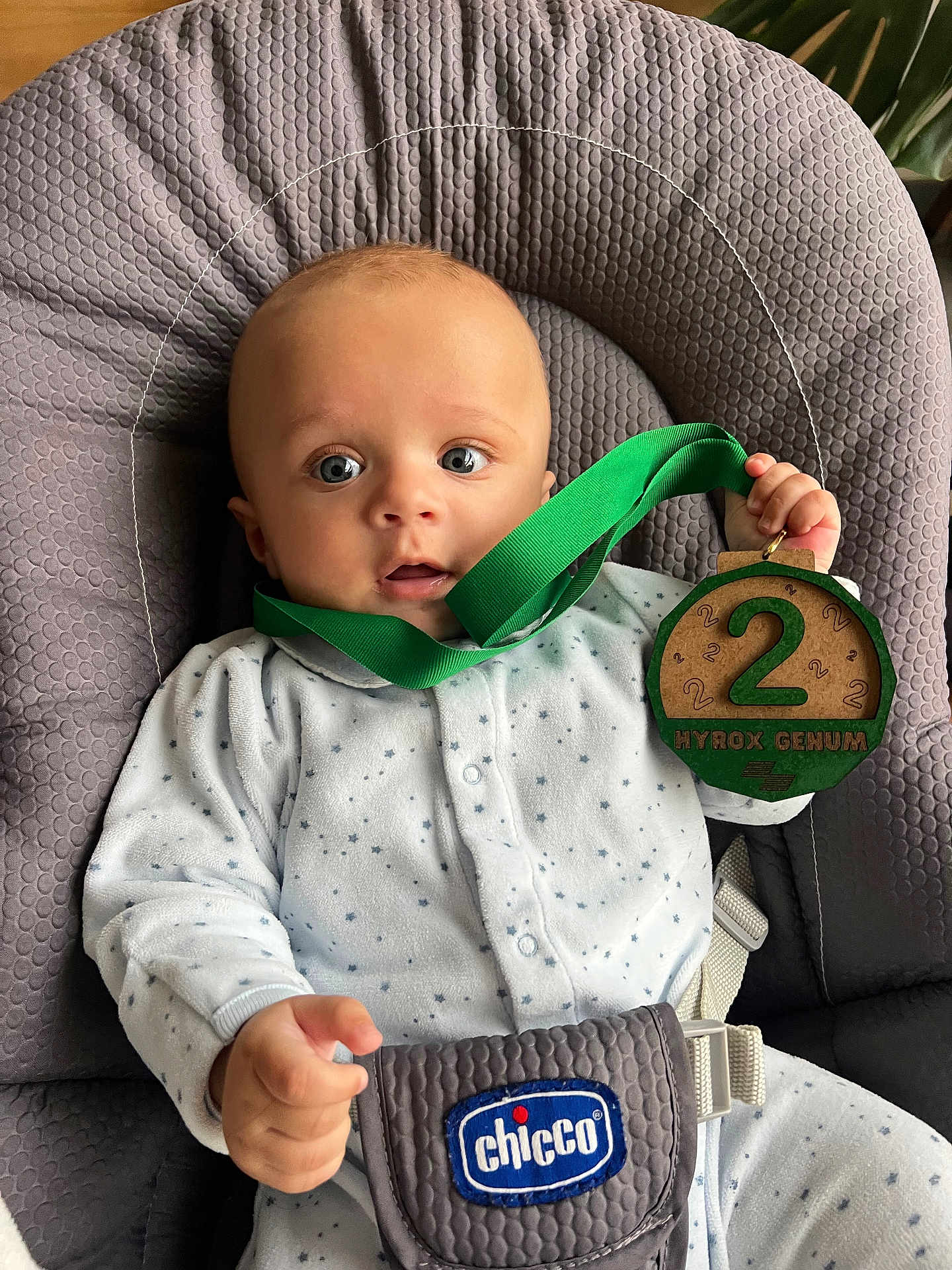 Léonard participe au concours pour gagner de l'argent avec cette photo : baby, infant, onesie, baby_seat, chicco, medal, green_ribbon, wooden_medal, face, blue_eyes, hand, clothing, indoor, cute, child, expression, comfort, sitting, young_child, portrait