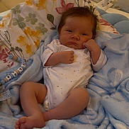 Elie participe au concours pour gagner de l'argent avec cette photo : baby, blanket, clothing, comfort, couch, cute, expression, face, floral_pattern, foot, furniture, hand, indoors, infant, onesie, person, pillow, resting, soft_texture, young_child