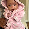 baby, infant, pink_robe, hood, cute, curious, person, hand, clothing, indoor, skin, face, eyes, expression, holding, soft_texture, warm, newborn, portrait, child