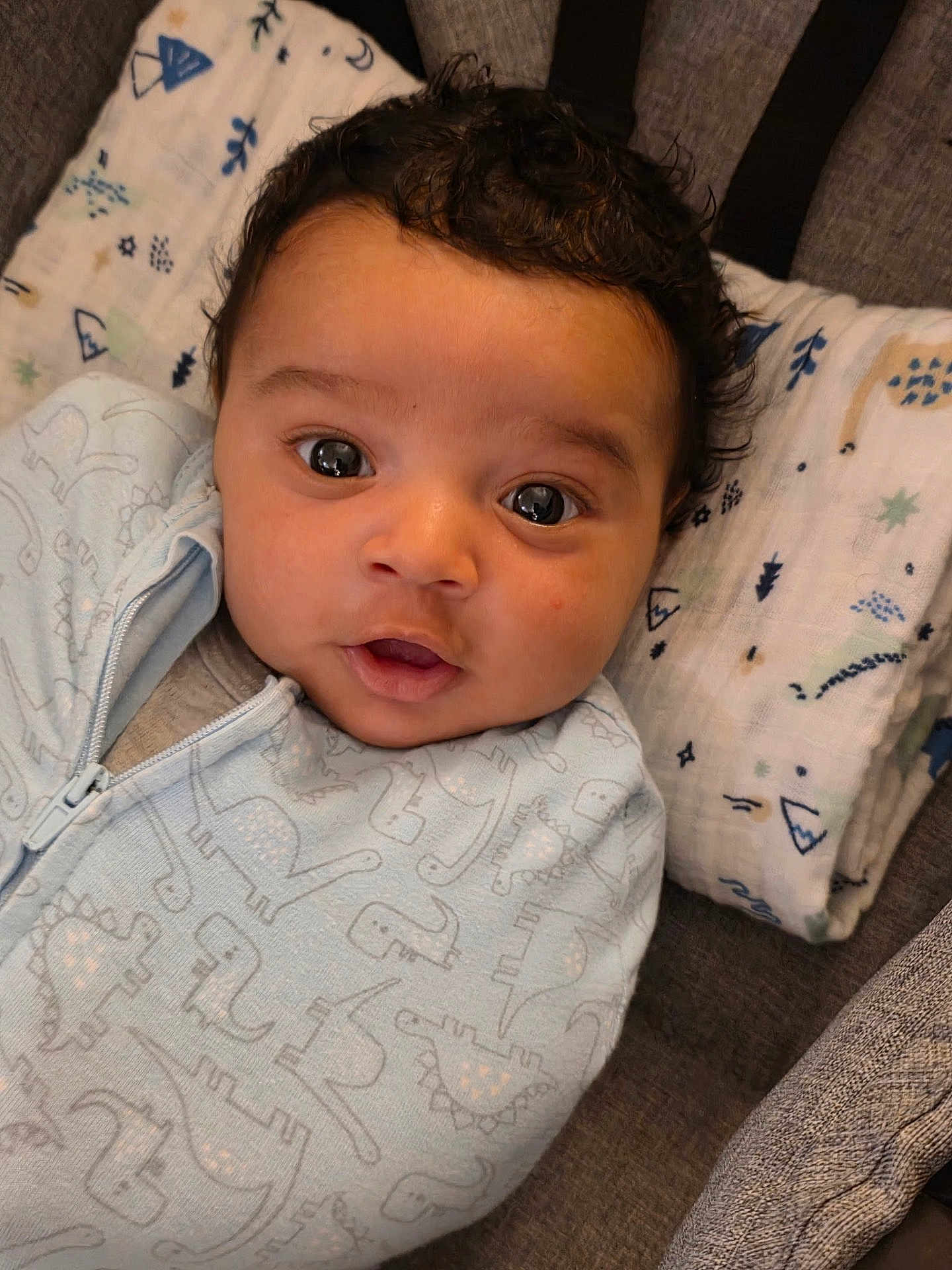 Khaza joined the competition — help win amazing prizes! baby, infant, face, eyes, sleepwear, dinosaur_pattern, blanket, cushion, soft_fabric, cute, indoors, portrait, child, cozy, lying_down, curly_hair, expression, comfort, close_up, young