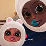 face_filter, cartoon_eyes, bear_hat, fluffy_hat, indoor, person, child, adult, brown_skin, big_eyes, pink_blanket, cozy, portrait, funny_faces, cute, family, digital_effect, selfie, hat, warm_clothing
