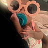baby, pacifier, sunglasses, flower_shaped, infant, hand, clothing, blanket, indoors, cute, portrait, sleepwear, person, face, small_child, resting, soft_lighting, curly_hair, pink, cozy
