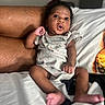 baby, infant, child, face, expression, clothing, bed, blanket, pillow, pineapple, hand, foot, skin, person, indoor, cute, surprised, curious, relaxing, casual