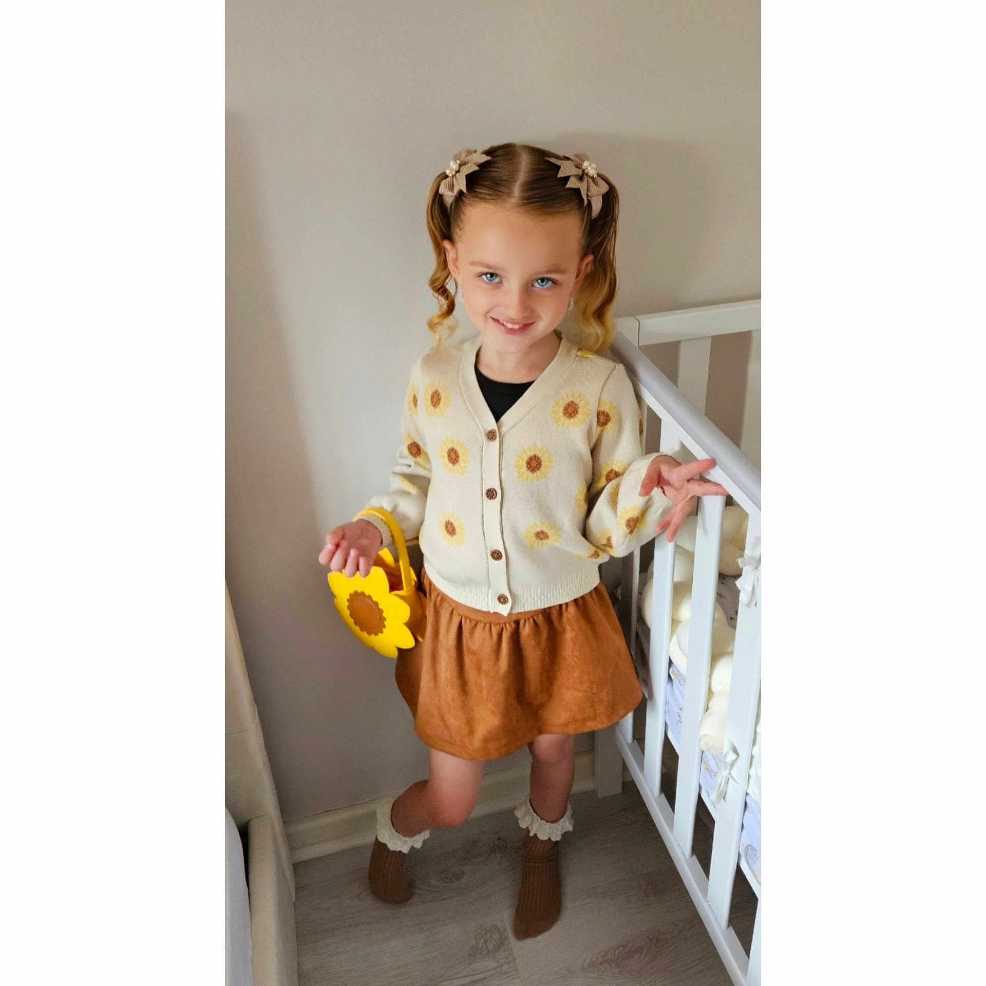 Ryla joined the competition — help win amazing prizes! blue_eyes, cardigan, child, crib, cute, fashion, flower_pattern, girl, hair_clips, home, indoor, light_skin, pigtails, playful, pose, skirt, smile, socks, sunflower_purse, wooden_floor