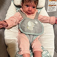 Evangeline is registered to the contest to win money with this photo: baby, infant, child, face, pink_clothing, striped_clothing, baby_seat, cushion, safety_harness, indoor, cute, small_hands, small_feet, soft_toys, gray_background, closeup, portrait, expression, hair, eyes