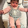 baby, infant, child, face, pink_clothing, striped_clothing, baby_seat, cushion, safety_harness, indoor, cute, small_hands, small_feet, soft_toys, gray_background, closeup, portrait, expression, hair, eyes