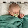baby, bed, blanket, cozy, eyes_closed, face, fur_pillow, green_blanket, hand, head, infant, newborn, nursery, pacifier, peaceful, pillow, sleeping, soft_texture, swaddle, wooden_headboard