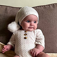Ariana participe au concours pour gagner de l'argent avec cette photo : baby, infant, child, knitwear, hat, pom_pom, couch, brown, white, button, texture, sitting, cute, portrait, indoors, soft_lighting, hand, face, eyes, clothing
