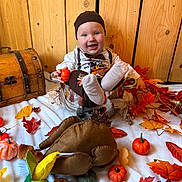 Samson participe au concours pour gagner de l'argent avec cette photo : baby, child, pot, metal, pumpkins, autumn, fall, leaves, orange, yellow, plush_toy, turkey, smiling, hat, wooden_background, festive, decorations, white_blanket, cute, happy