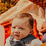 Jaxson J is registered to the contest to win money with this photo: baby, infant, denim_overalls, clothing, face, hands, outdoor, blanket, expression, person, cute, young_child, portrait, skin, hair, sitting, natural_light, closeup, child, casual