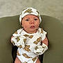 baby, newborn, infant, teddy_bear_print, onesie, mittens, hat, cushion, green_chair, cute, child, person, portrait, indoor, soft_light, seated, expression, small, human, adorable