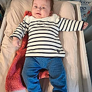 Athénaïs a rejoint le concours — aidez-le/la à gagner de superbes lots ! baby, baby_clothes, blue_pants, changing_pad, child, clothing, cute, expression, face, furniture, happy, head, indoor, infant, lying_down, person, smiling, striped_shirt, toddler, towel