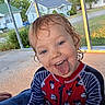 child, toddler, portrait, smiling, tongue_out, silly_face, outdoor, backyard, patio, canopy, swimsuit, mickey_mouse, striped_sleeves, wet_hair, blue_eyes, sitting, residential_street, houses, trees, sunlight