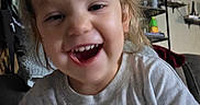 Celica joined the competition — help win amazing prizes! child, toddler, smiling, laughing, portrait, face, indoors, home, cap, blond_hair, gray_shirt, cartoon_shirt, flowers, shelf, furniture, close_up, happy, teeth, seated, photograph