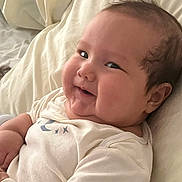 Viggo joined the competition — help win amazing prizes! baby, infant, smile, face, cheeks, bed, blanket, clothing, cute, lying_down, skin, head, hair, person, indoors, soft, expression, baby_garments, cozy, happy