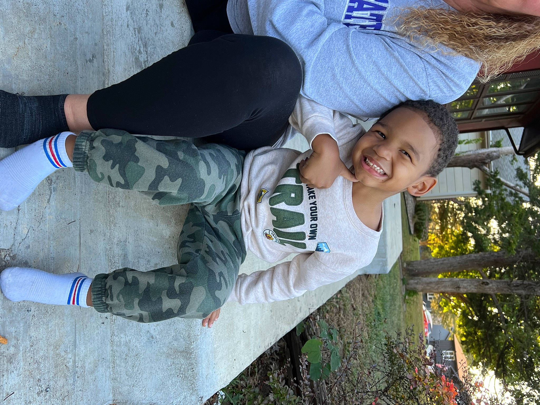 Karter is registered to the contest to win money with this photo: baseball_cap, cap, child, eyewear, fun, gesture, grass, happy, hat, joy, knee, leisure, person, plant, recreation, sitting, smile, t_shirt, thigh, toddler