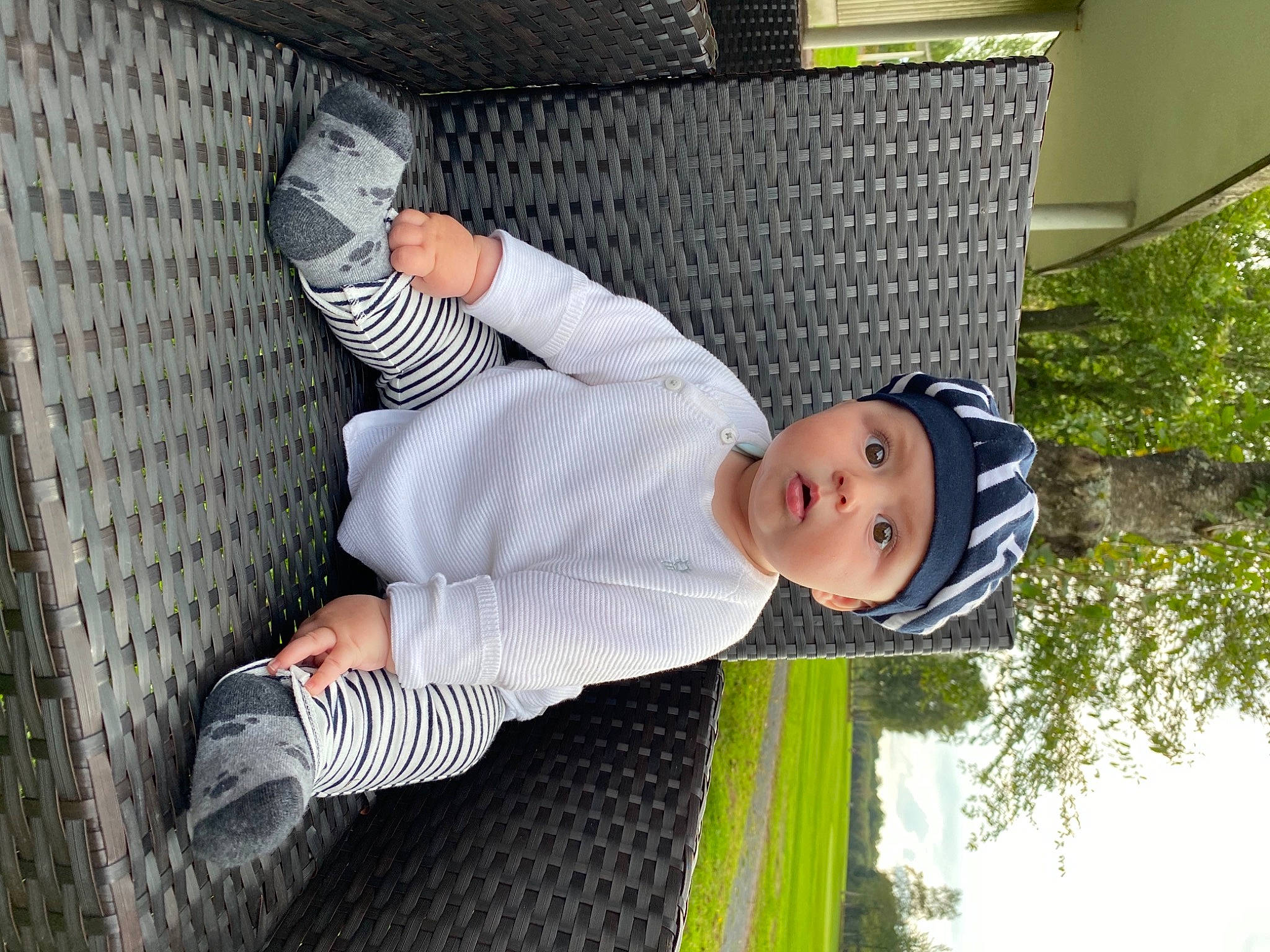 Robin participe au concours pour gagner de l'argent avec cette photo : baby, baby_toddler_clothing, child, comfort, foot, fun, grass, hat, headwear, human_leg, knee, leisure, pattern, person, plant, sitting, sky, surprise, toddler, tree