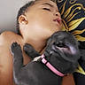 child, sleeping, puppy, dog, black_dog, pink_collar, cuddle, close_up, indoor, pillow, pattern, bedroom, resting, cute, pet, friendship, tender, cozy, nap, young
