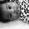 Naveah is registered to the contest to win money with this photo: baby, face, portrait, black_and_white, infant, clothing, pattern, spotted, lying_down, child, cute, eyes, skin, person, young, expression, head, indoors, monochrome, soft