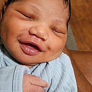 Brezdin is registered to the contest to win money with this photo: baby, newborn, smiling, face, hand, clothing, blue_outfit, skin, person, infant, sleeping, closeup, cute, happy, child, portrait, human, toddler, resting, warm_lighting