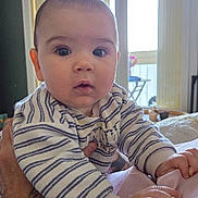 émile participe au concours pour gagner de l'argent avec cette photo : baby, infant, child, striped_sweater, hands, indoor, window, natural_light, curious, person, portrait, soft_lighting, cozy, holding, human, cute, expression, face, young, warm