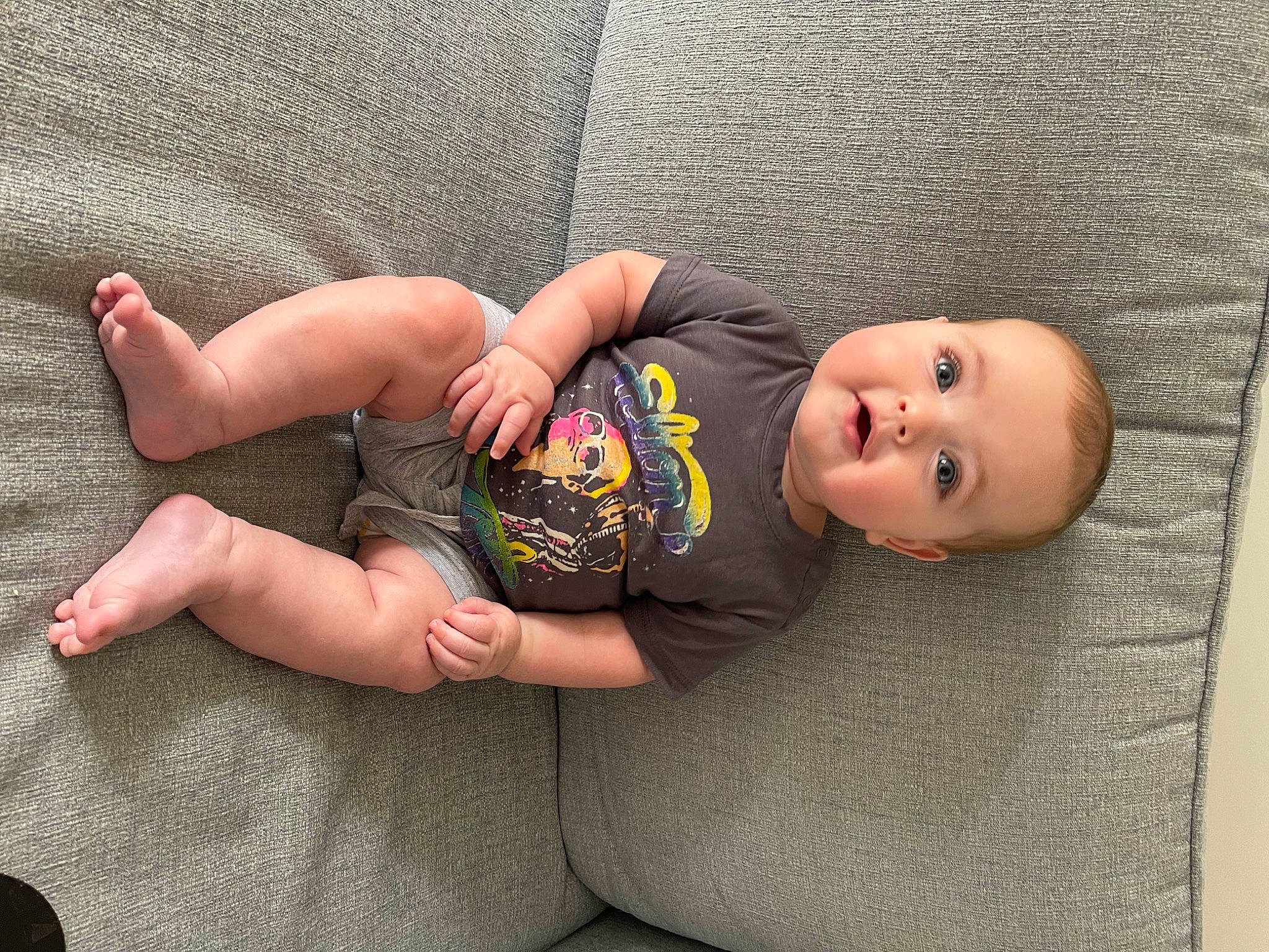 Theo is registered to the contest to win money with this photo: baby, baby_toddler_clothing, barefoot, chest, child, comfort, eye, flooring, foot, grass, grey, human_leg, joint, knee, leg, person, skin, thigh, toddler, trunk